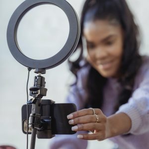 woman adjusting her phone attached to a tripod with a ring light